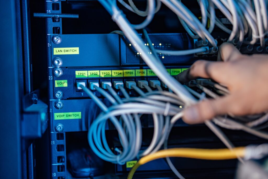 Technician working with ethernet cables and rack-mount switches for Gigabit Ethernet.